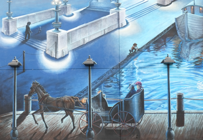 horse drawn carriage passing in front of the erie canal where a man is tying up a boat, two people in the carriage, 