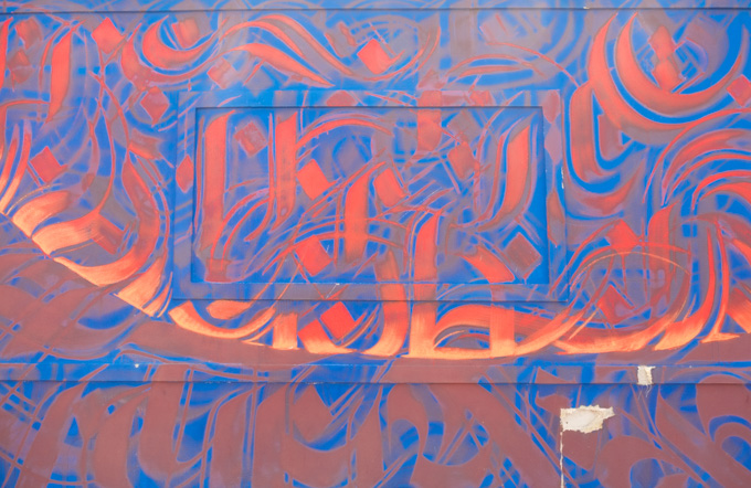 part of calligraphy type mural by nepalese artist sneha shresta, in reds and oranges on blue background