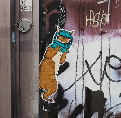 graffiti sticker on metal, a squirrel wearing a turquoise hat