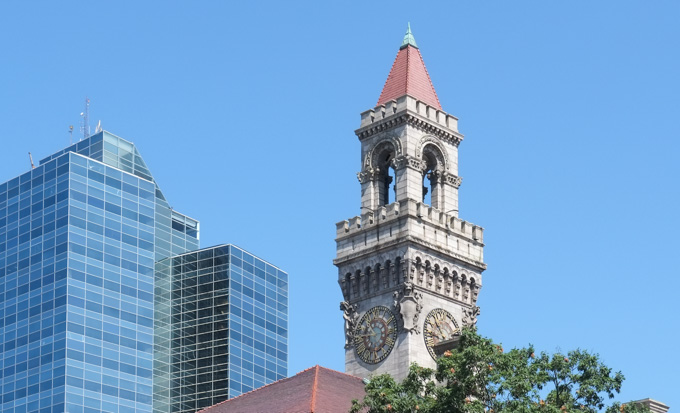 clock tower in downtown worcester on old stone building, with newer glass skyscrapers behind it
