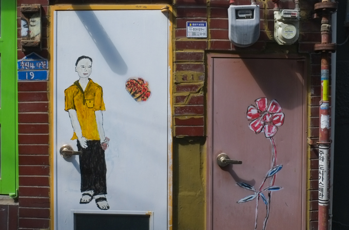mural on a wall of a man in yellow shirt and black pants, and sandals, standing there