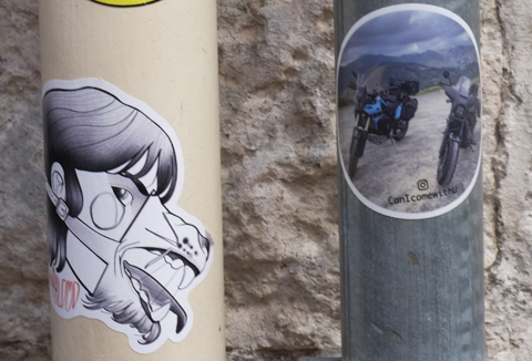 sticker graffiti, one with 2 motorcycles and one with man in wolf mask