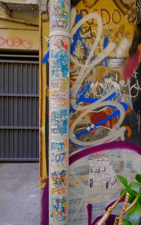 on a pole, or pipe, in an alley, covered with pasteups, paper, posters, that are words written artistically on old music scores