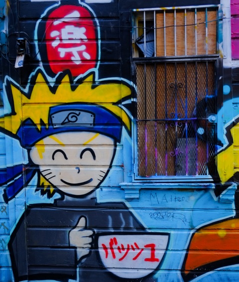 street art painting of a blond boy with blue headband, with a large bowl of food, probably a manga character, naruto?