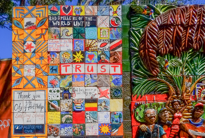 hand decorated ceramic tiles arranged in a mosaic as street art on a building in a park in Port Phillip Australia, including words like trust, and bad spellers of the world untie