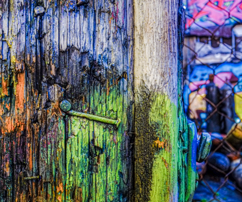 bent nail in wood utility pole, spray painted pole in blues and green, graffiti