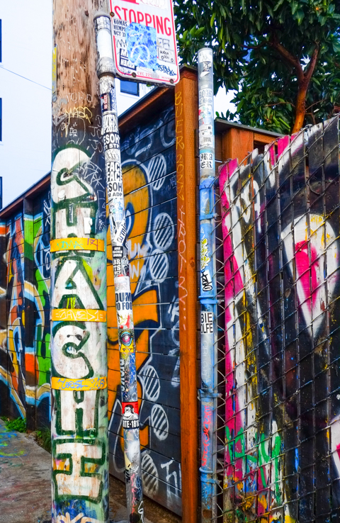 poles and walls in alley covered with graffiti and street art