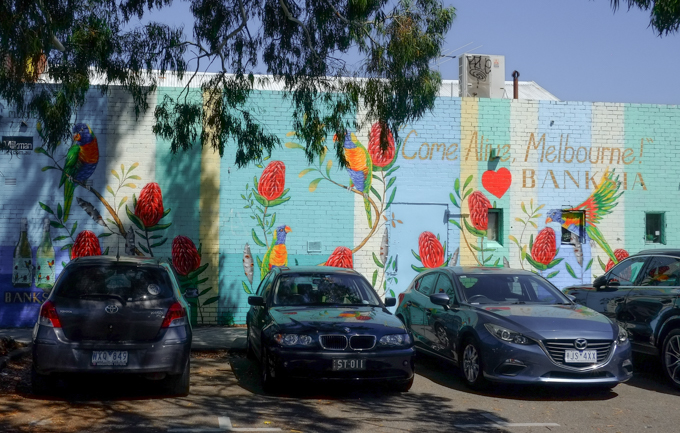 cars parked in front of a mural