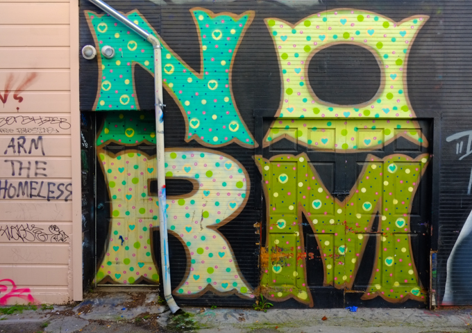 four large letters painted on a black garage door, N O R and M. Spells norm