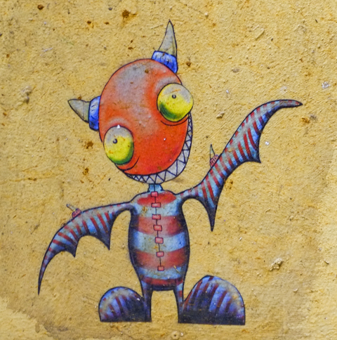graffiti, little gragon-like character with big orange head, little wings as arms that are red and blue striped, big yellow eyes, by stenandoli