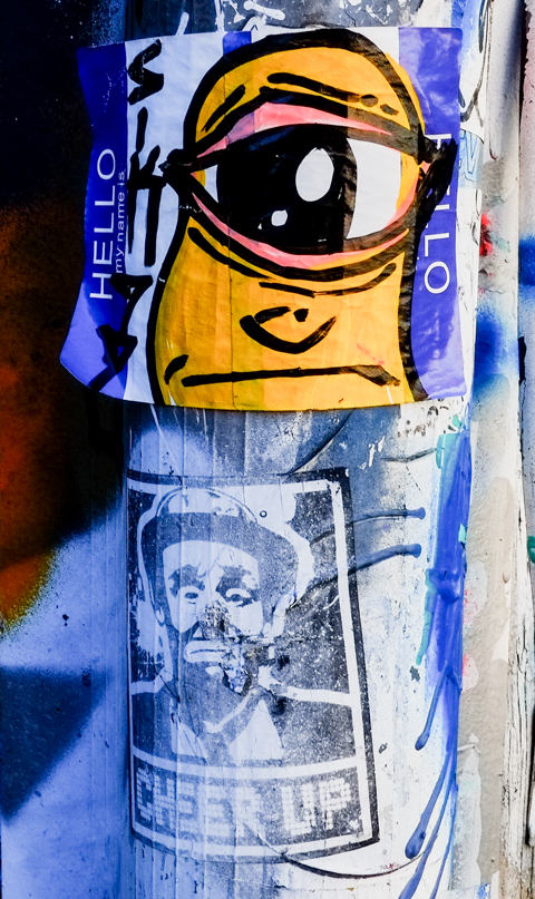 two stickers on a pole, one with sad clown that says cheer up