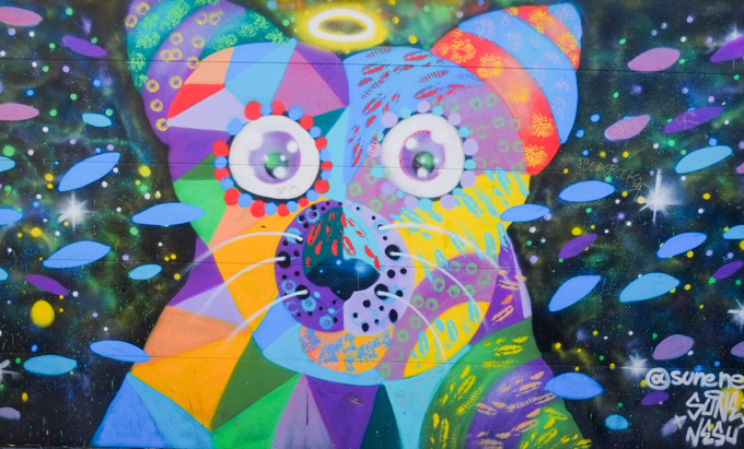 mural that is an abstract animal shape with big ears and button-like eyes, whiskers, in geometric shapes, many colours, artist is sune nesu