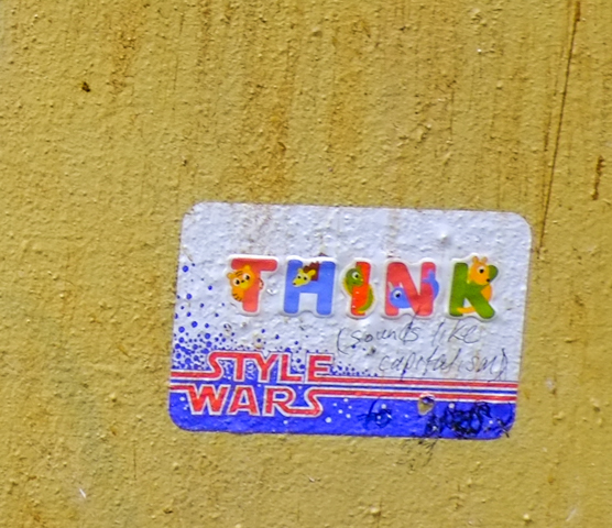 sticker says think in decorated capital letters, sticker is a style wars sticker, someone has written in ink, sounds like capitalism