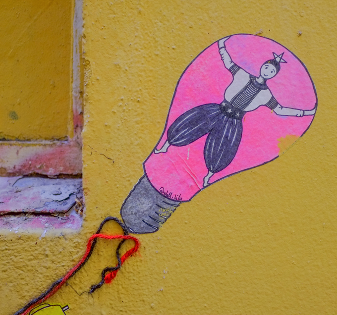 paper pasteup on yellow wall, shape of a light bulb, by wall lilo