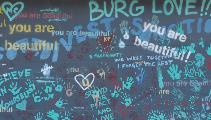 wall covered with words and messages such as you are beautiful, stand for peace and love, 