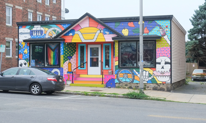 one storey building, small pointed arch over entrance, two large windows, front is covered with mural