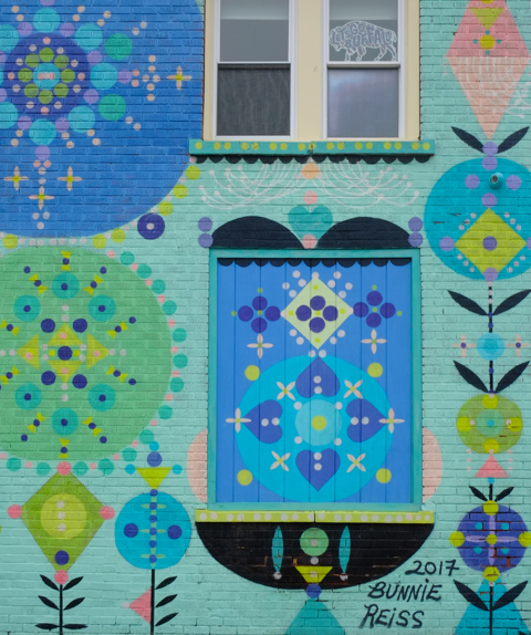 a section of mural by Bonnie Reiss, stylized floral motifs in blues and purples on a bright turquoise background