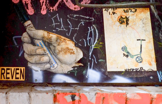 paper paste up graffiti, a realistic image of a hand holding a marker, and a drawing of a blue scooter with an orange balloon