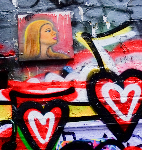 small graffiti of a woman's portrait, with spray painted hearts by it