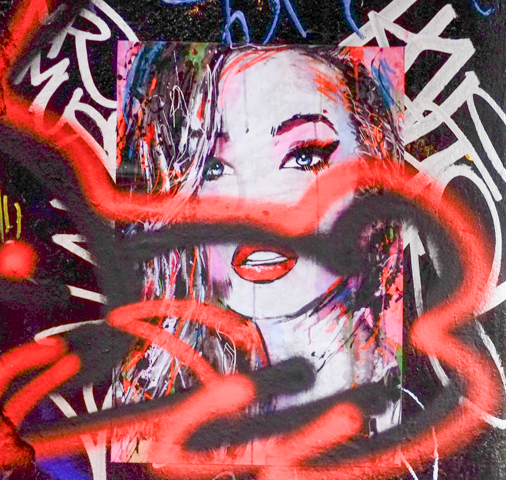 street art painting, poster, of a woman's portrait, with red spray paint defacing it