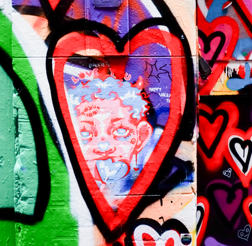 many graffiti spray painted hearts with some hand drawn small hearts with happy faces