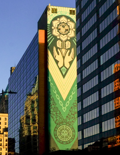 very tall mural on the side of building by Shepard Fairey, reflections of other buildings, 