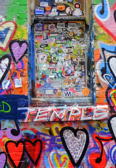 graffiti spray painted hearts covering window frame and wall, with stickers covering the window