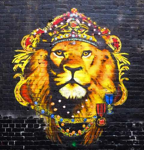 mural on a brick wall in Carson Place, a lion's head, wearing a crown, painted by Michael Che Romero