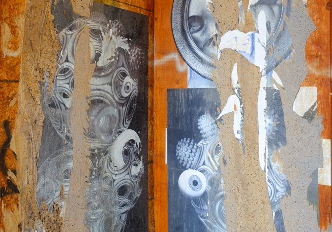 remnants of older paper paste up graffiti, torn, on plywood, in black and white images