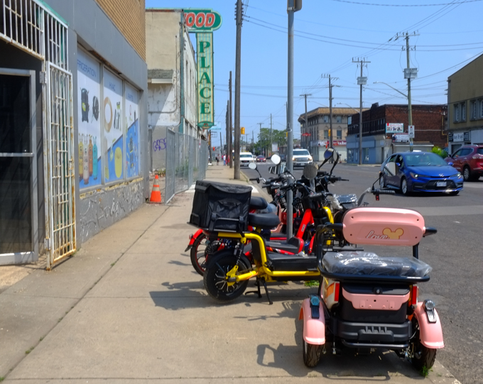 bicycles parked on the sidewalk outside a cycle shop, also a motorized wheelchair, scooter, in pink, Hamilton, Barton Street