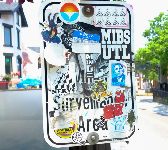 graffiti stickers covering a street sign including a blue hope sticker with portrait of Obama