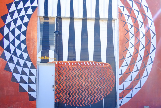 mural, with door in middle, circles made of triangles in black, on orange background
