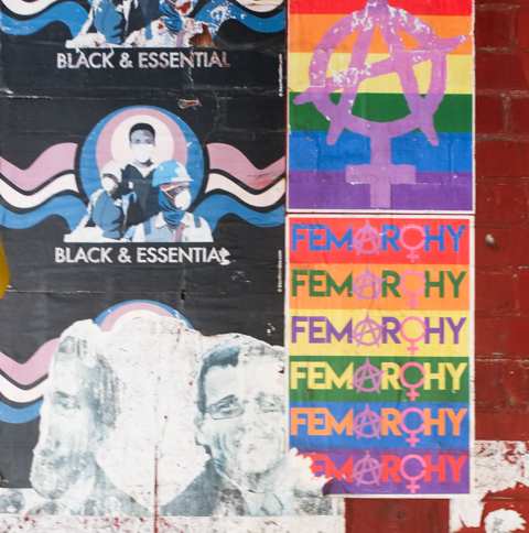 graffiti on a pole, including stickers that say femarchy in different colours