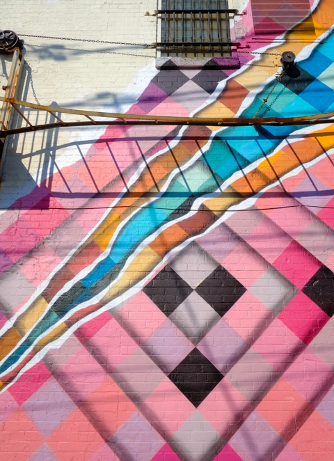 part of a mural by jason garcia, geometric patterns in different colours but mostly in pink 