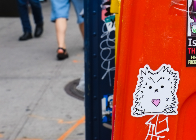 little graffiti sticker on a red surface, white furry creature with a little pink heart 