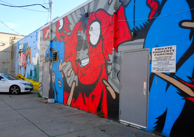 mural by Matt Gondek in a Wndosr Ontario Alley, large red costume, ripped to show grey skull below, 