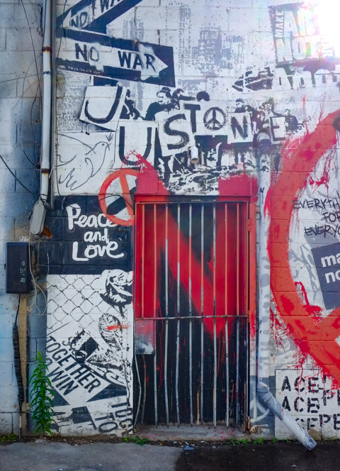 graffiti wall with black and white images, collage, of anti war protest, words saying peace and love, no war, just peace on, together we win, with red spray paint word no on top, 