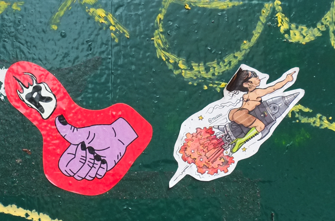 two graffiti stickers including one with a woman in thong bikini riding on a rocket