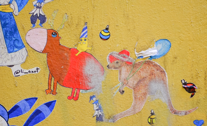 small Christmas themed paste ups on a yellow wall in Melbourne, Baptist Place, a kangaroo with a red hat