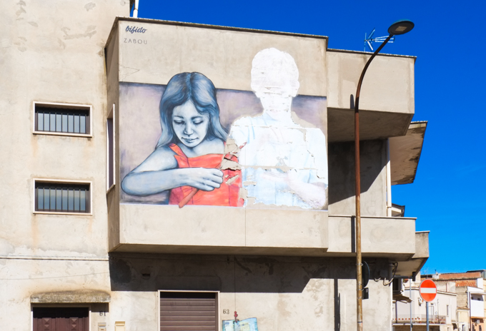 street art mural on side of residential building in Stornara, zabou and bifido collaboration, girl in orange top