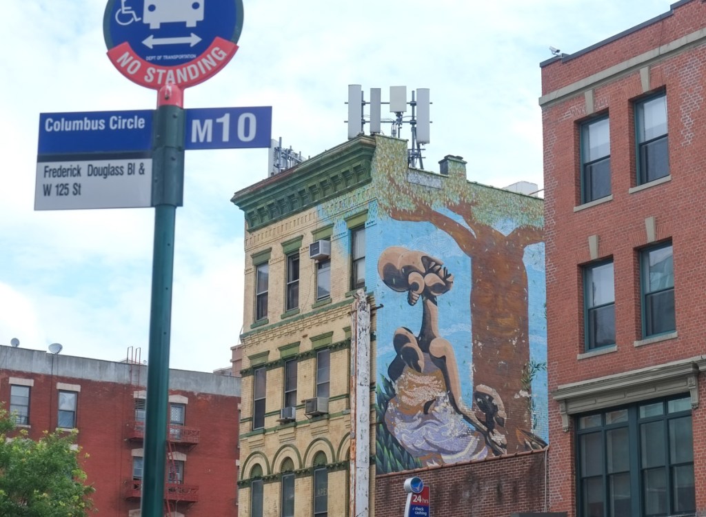 Mural by Alexandre Keto on the side of the Amsterdam News building in Harlem, 2 black women and a child under a baobab tree