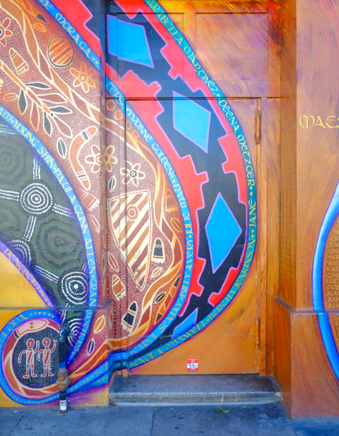 part of maestrapeace, a mural on the womens building, painting of symbols and patterns around a door