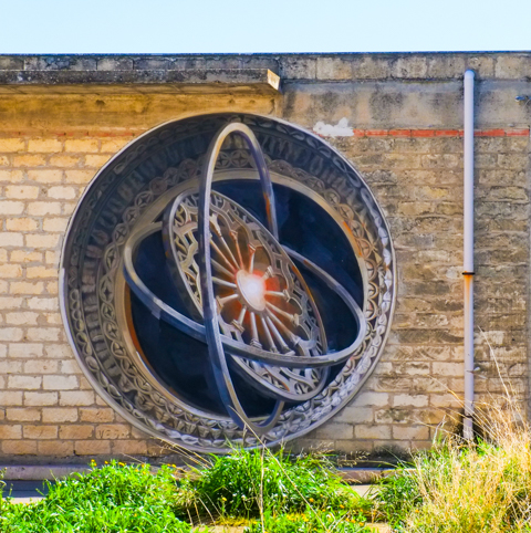 mural, three dimensional effect, mathematical instrument with rotating circles seems to come out of a brick wall , street art mural by Vesod