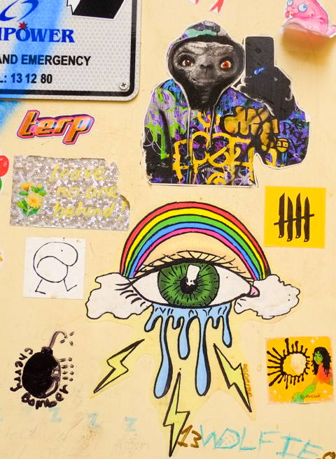 slaps on a yellow door, ET in a hoodie holding a smart phone, a black bomb cherry bomber, a green eye with tears under a rainbow, 