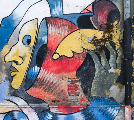 part of a mural in stornara italy by artists gods in love, title of crowd of fools, misshapen characters sometimes with multiple pairs of eyes, pointy fingers, strange shaped heads, etc