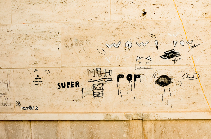 graffiti on a stone wall, drawn in black marker, the words super, meh, pop, and wow, as well as a cat's head