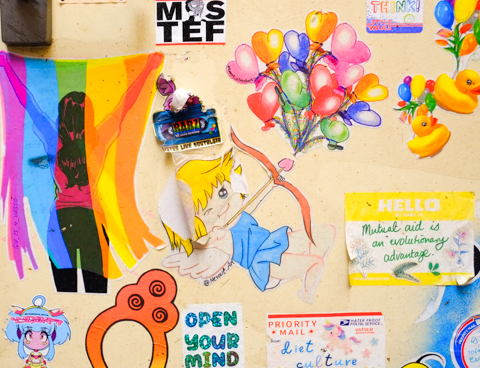 cupid with a bow and arrow, yellow rubber duckies, a woman with a rainbow scarf, open your mind, mutual aid is an evolutionary advantage, all graffiti on a door, 