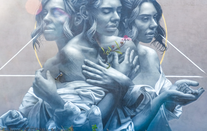 street art mural  by JDL, also known as Judith de Leeuw, which shows a woman in three similar poses combined into one person, middle one is holding a red flower