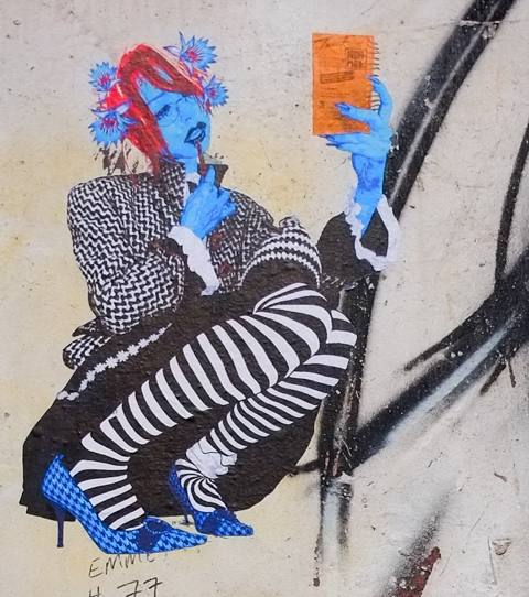 street art in ACDC lane, central Melbourne, artwork of a woman with blue hands and face, wearing black and white striped stockings, and a black and white jacket, holding an orange book while smoking a pipe