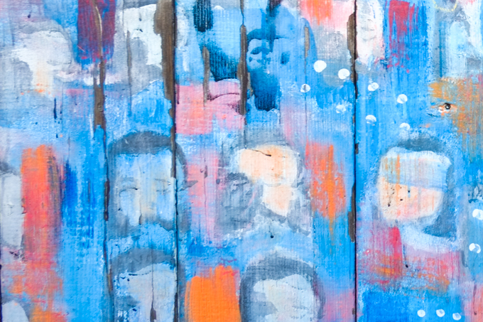 street art mural on a wood fence in balmy alley, mission district in san francisco, bottom part painted blue, stencils of faces, shapes and white dots, vine growing over top